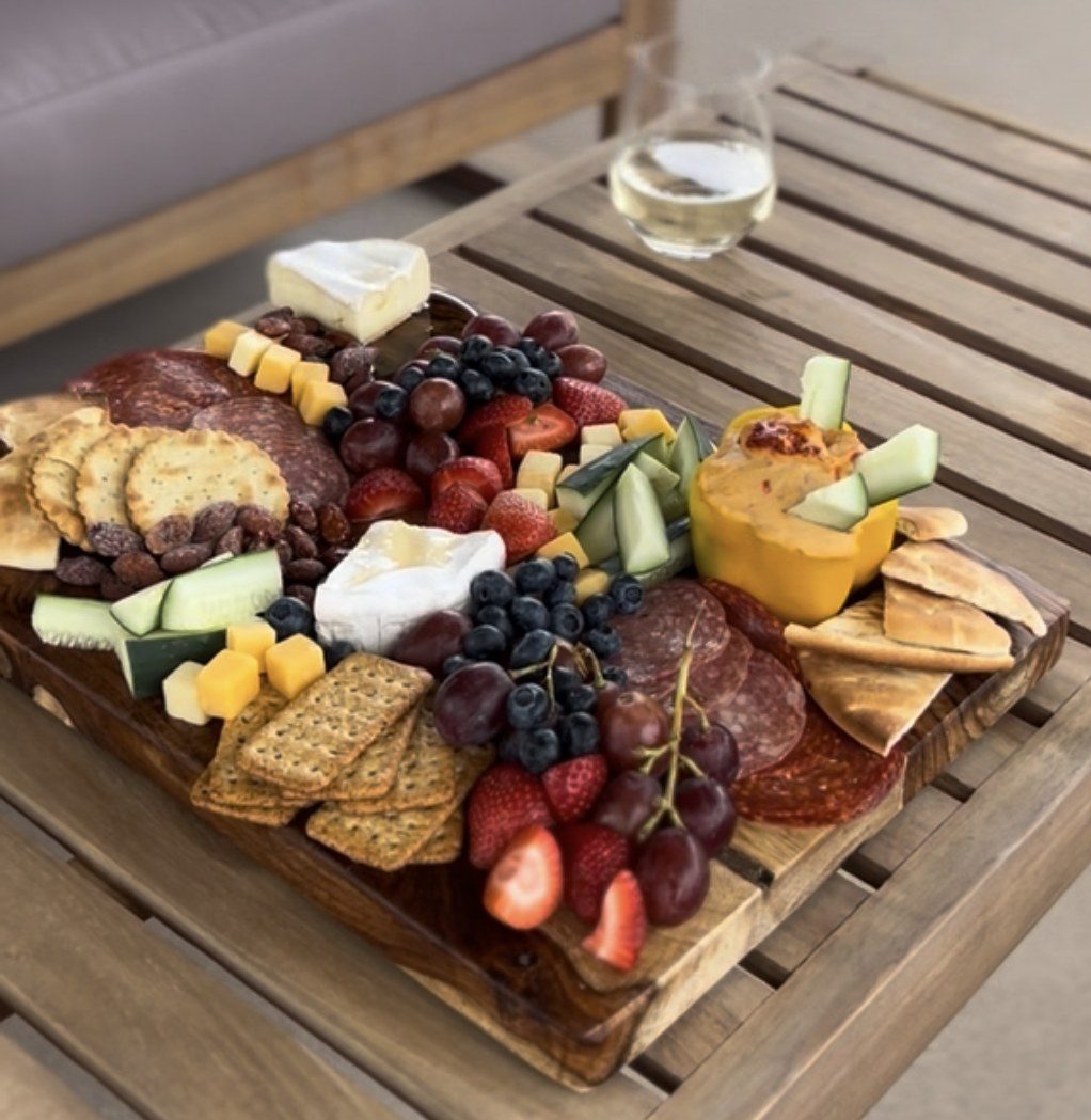 Charcuterie board with cheese, crackers, fruit and wine on outdoor table
