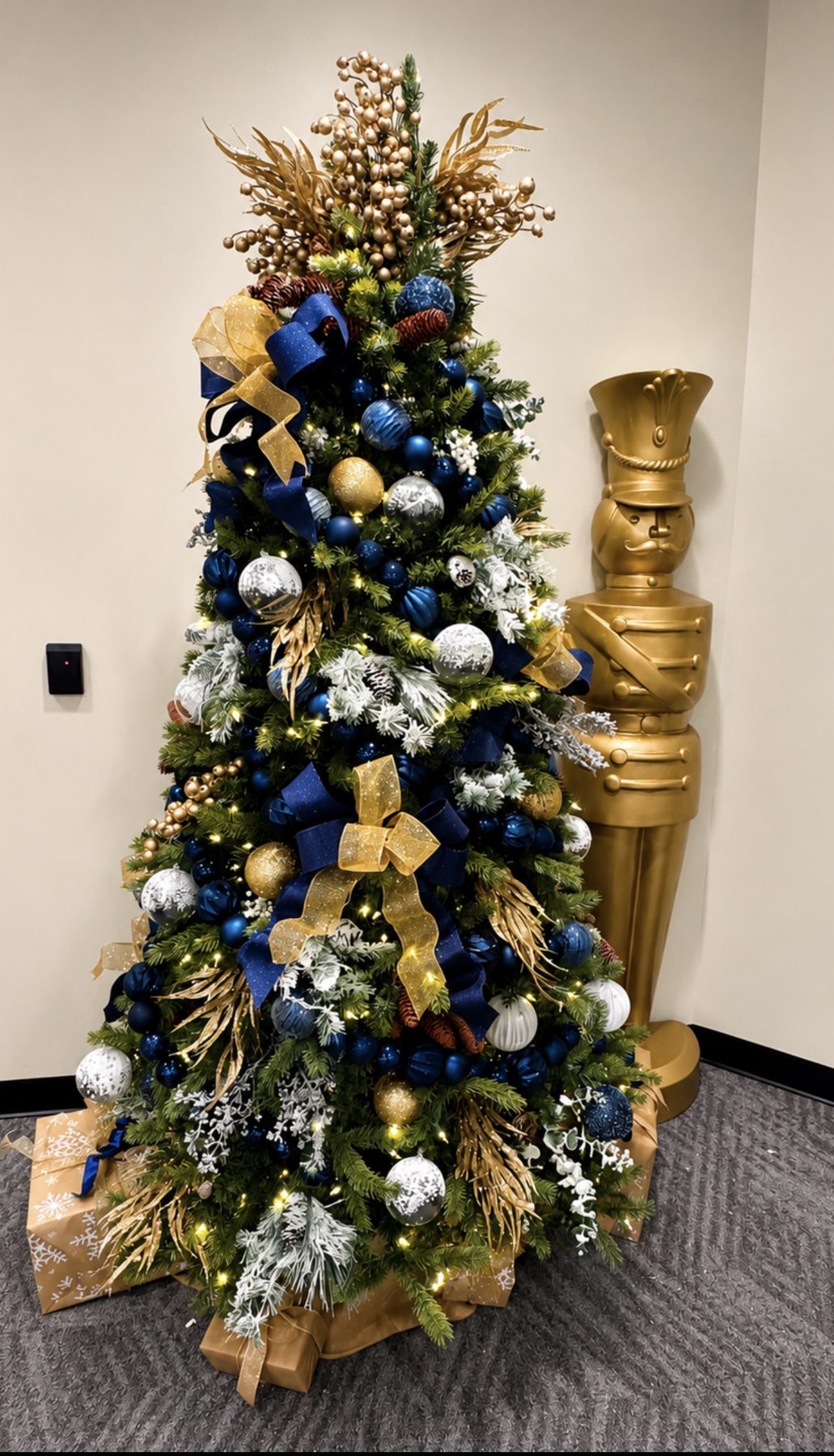 Navy and gold holiday tree installation with nutcracker statue