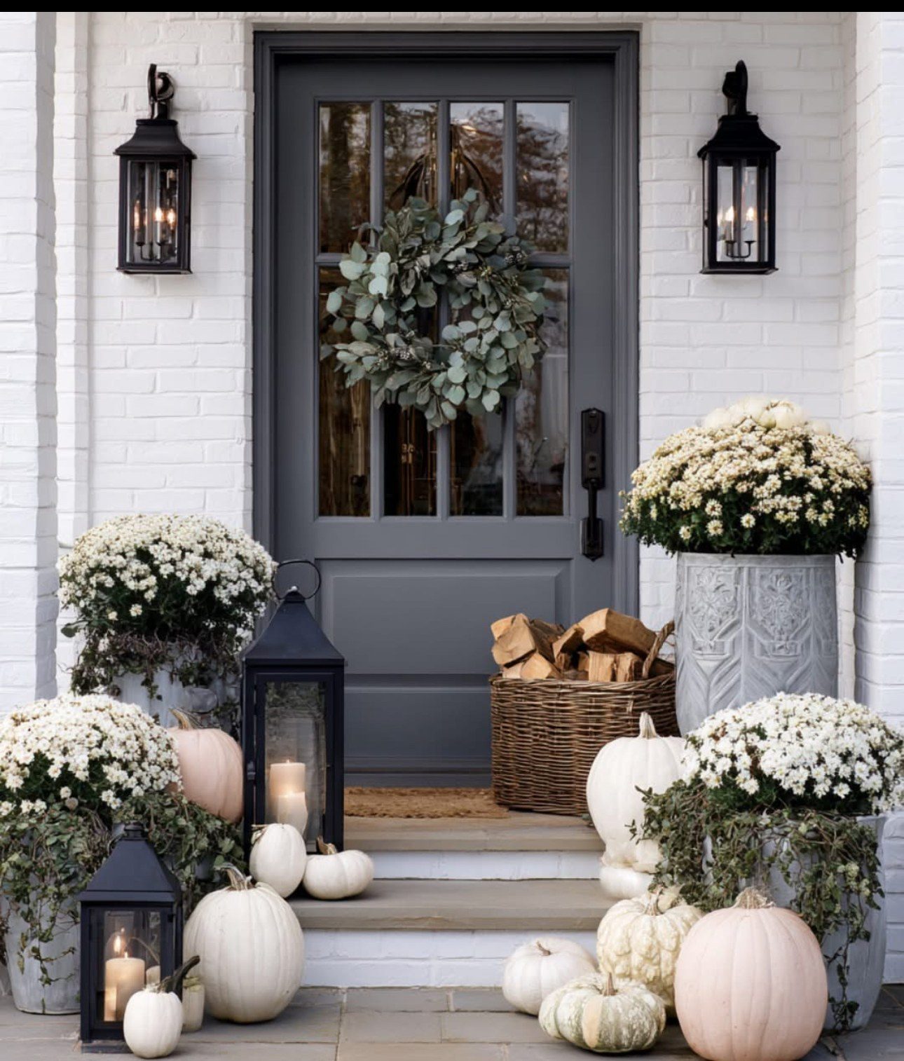 Front porch styled with mums, white pumpkins and lanterns